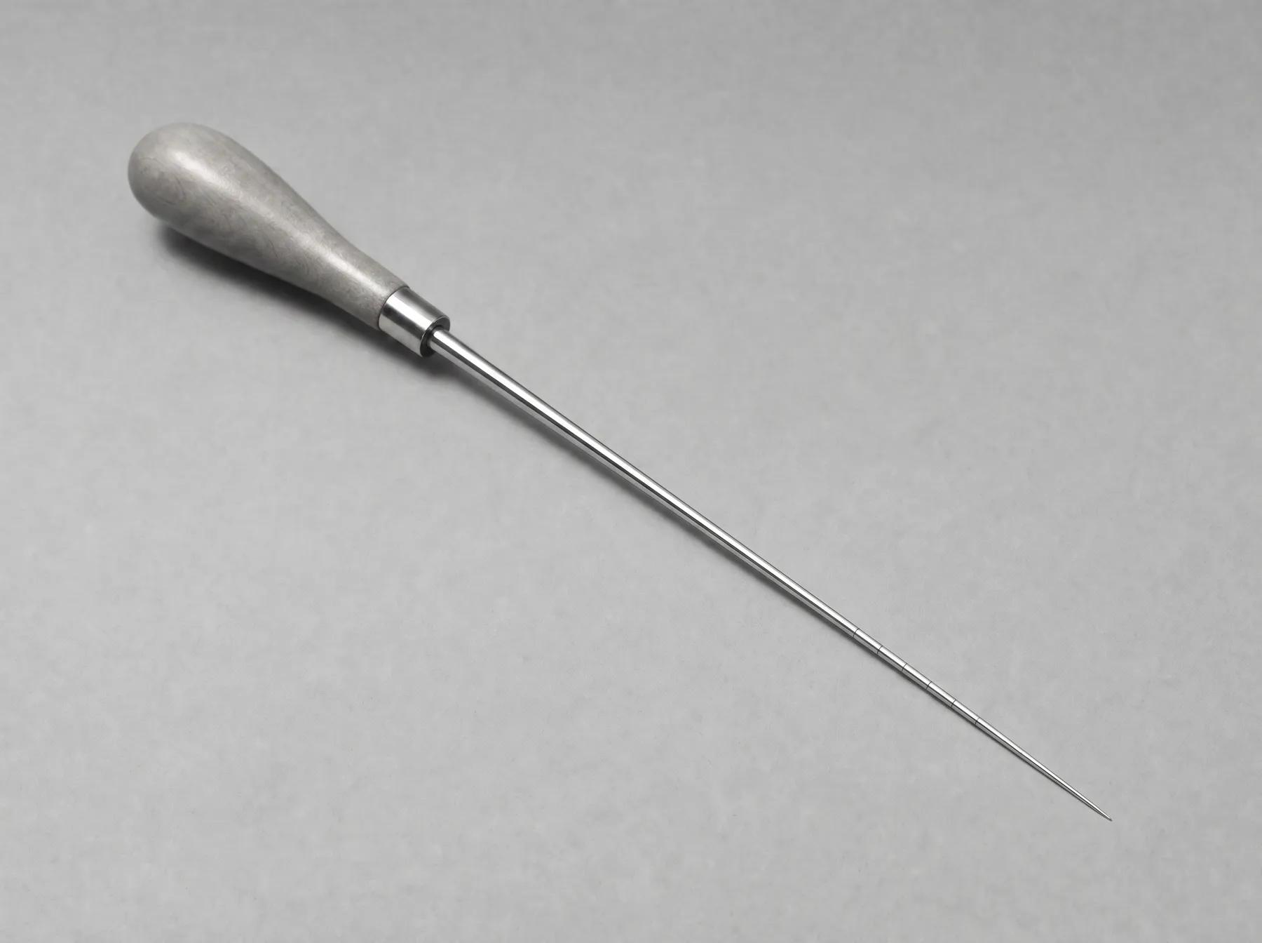 An ice pick against a gray background