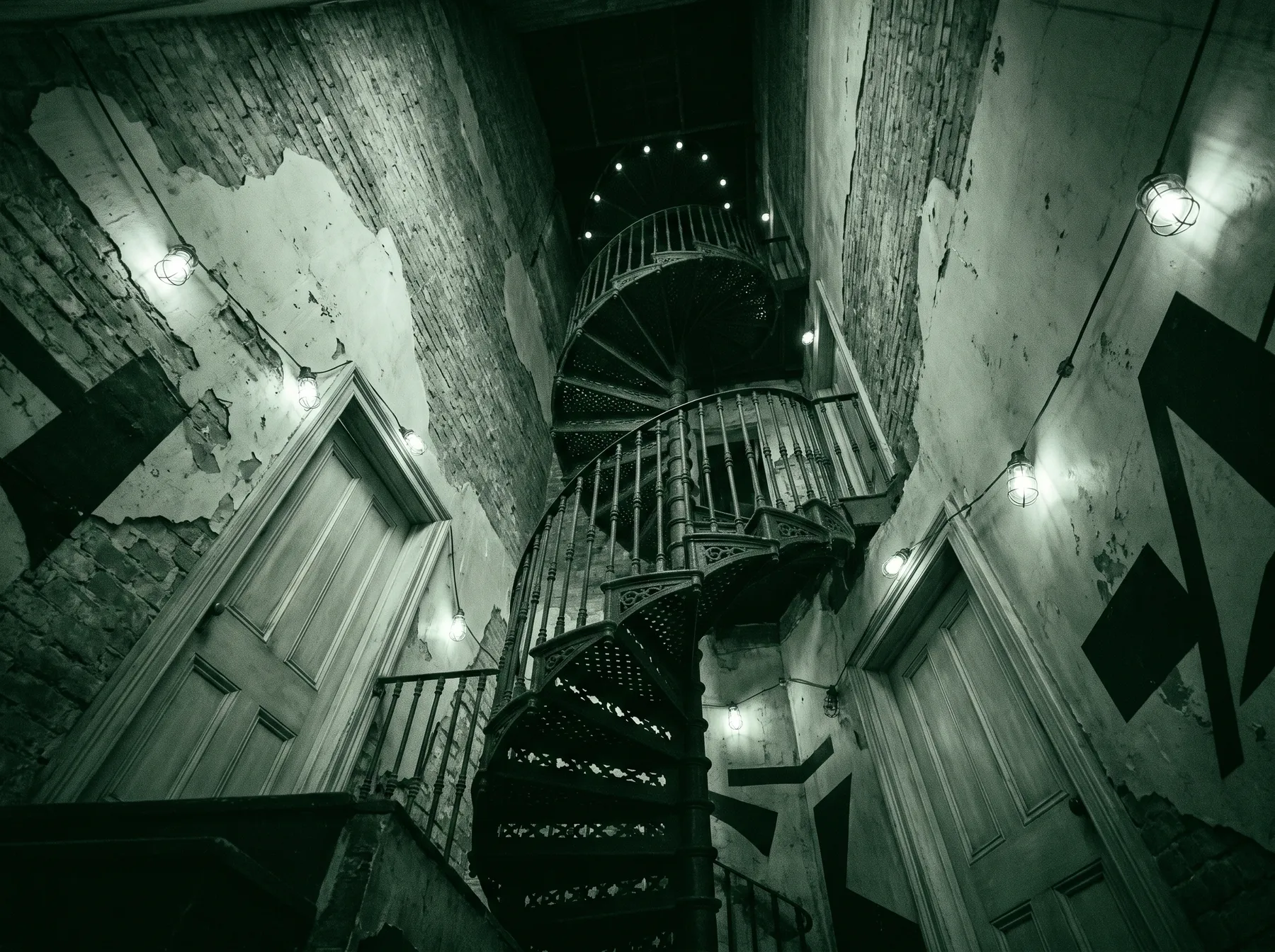 A spiral staircase seen from below in a shadowed stairwell