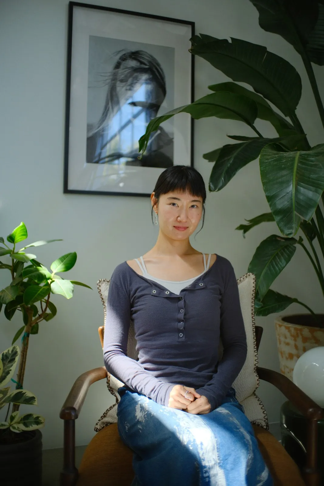 Mengqing Yuan seated beside leafy plants